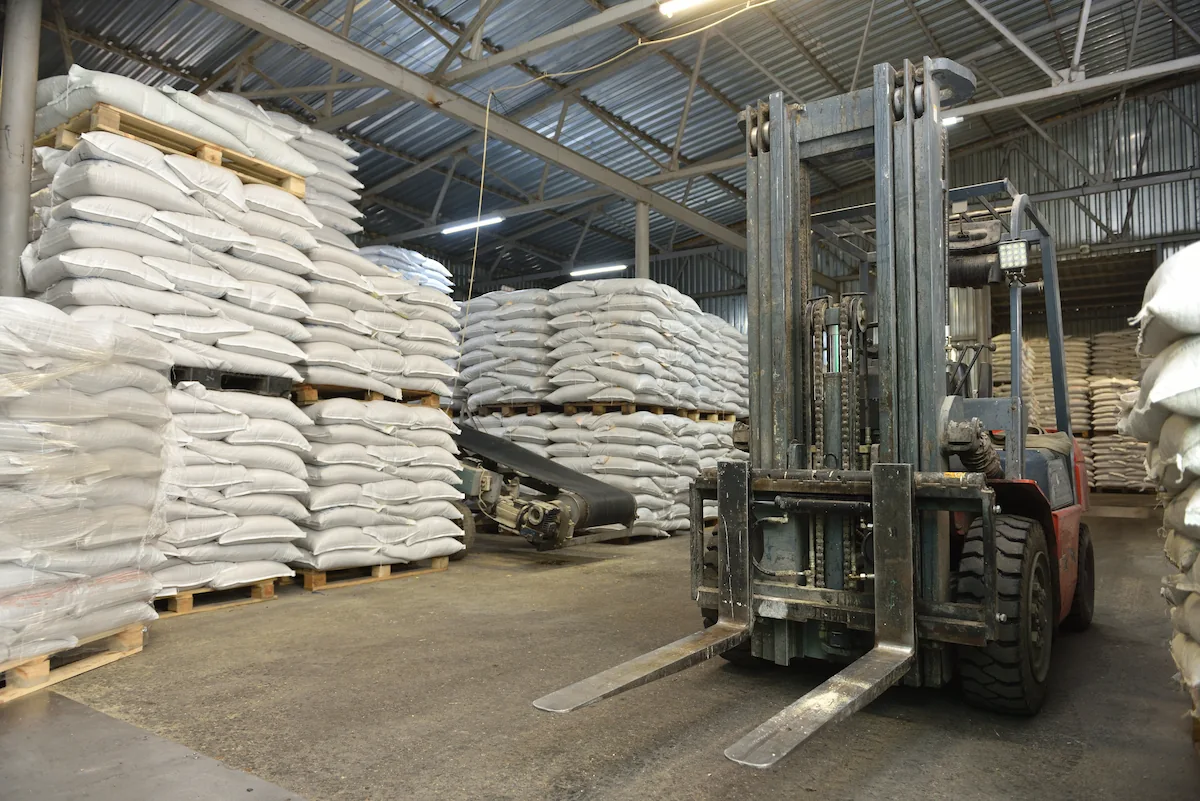 tumpukan bahan baku dan forklift di raw material warehouse