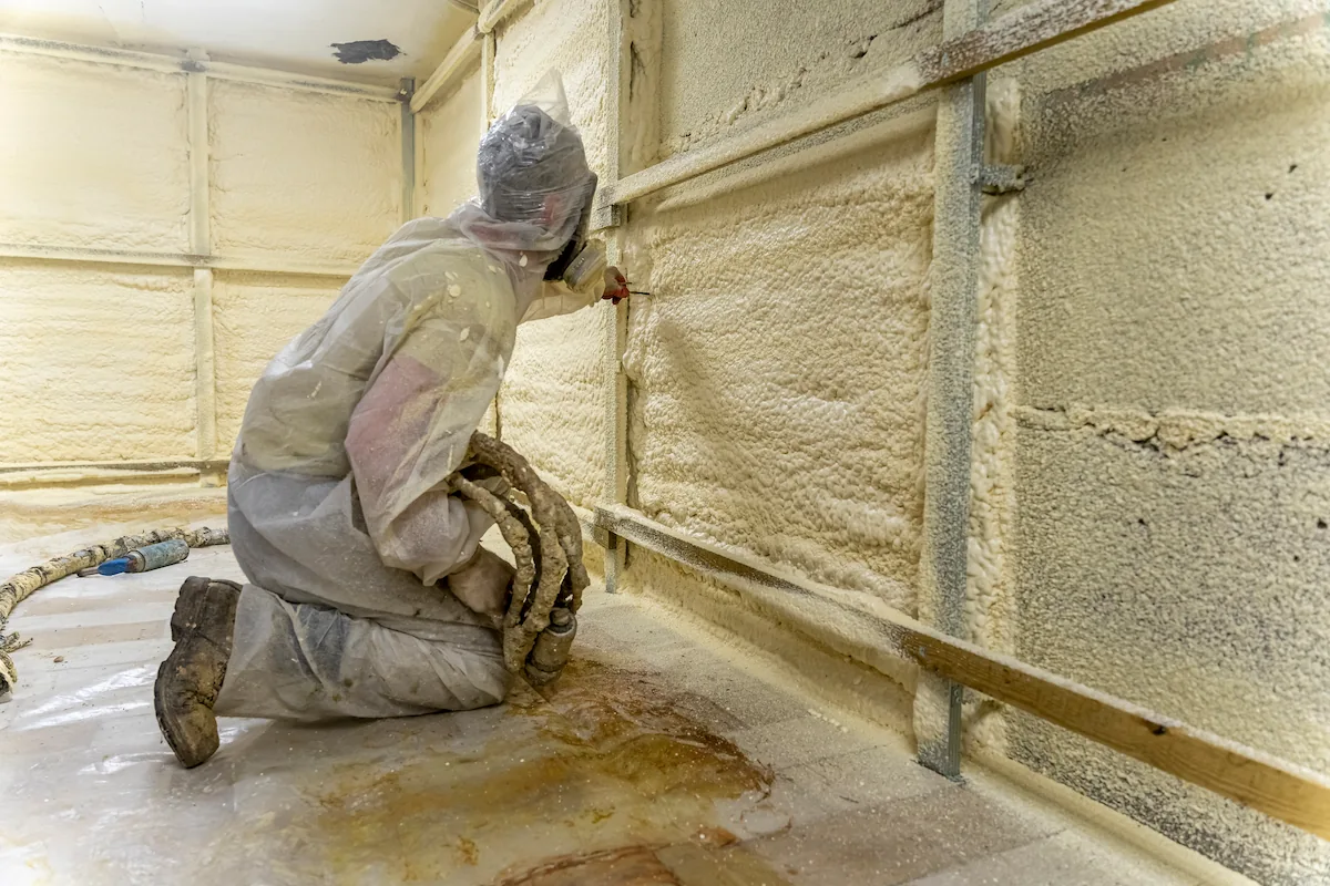 seorang teknisi menyemprotkan polyurethane foam untuk insulasi dinding bangunan