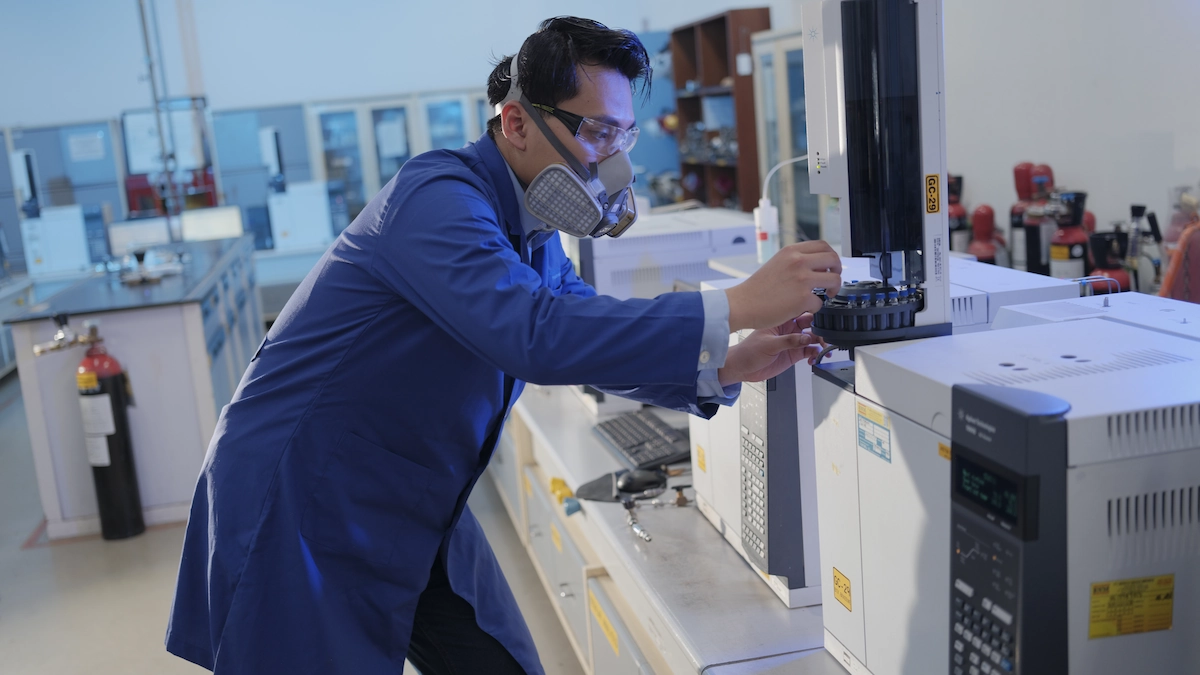 seorang teknisi sedang memasukkan bahan kimia ke dalam alat di laboratorium